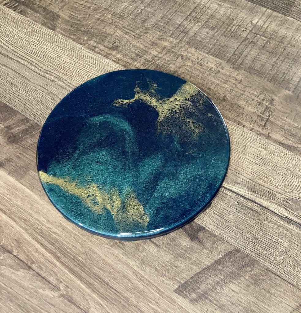 Wooden lazy Susan covered with hand-poured epoxy resin in hues of dark blues and greens with ribbons of gold.